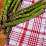 Asparagi freschi in un piatto, pronti per essere cucinati e controllati al tatto.