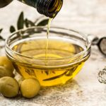 Bottiglia di olio extravergine d'oliva su sfondo naturale, simbolo di freschezza e qualità.