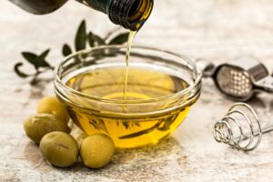 Bottiglia di olio extravergine d'oliva su sfondo naturale, simbolo di freschezza e qualità.