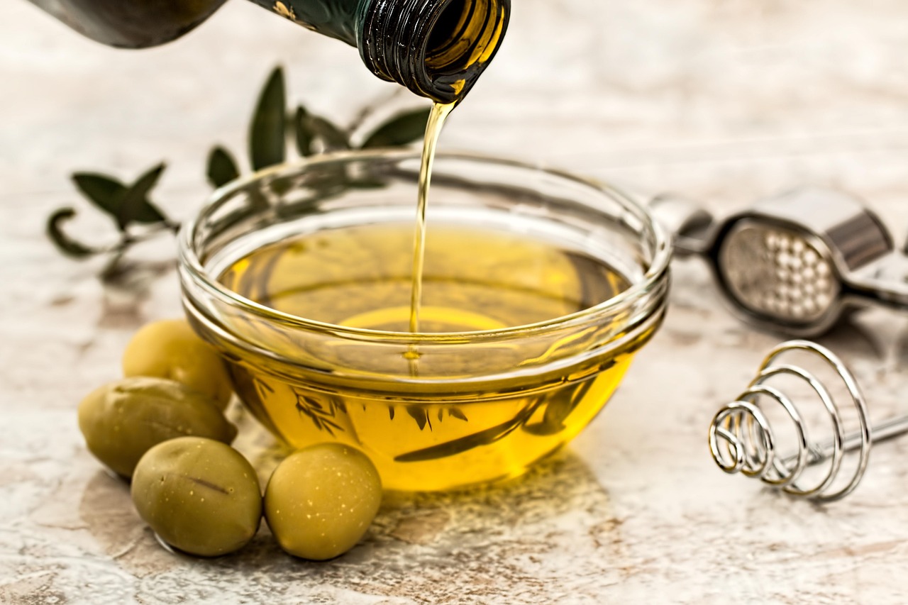 Bottiglia di olio extravergine d'oliva su sfondo naturale, simbolo di freschezza e qualità.