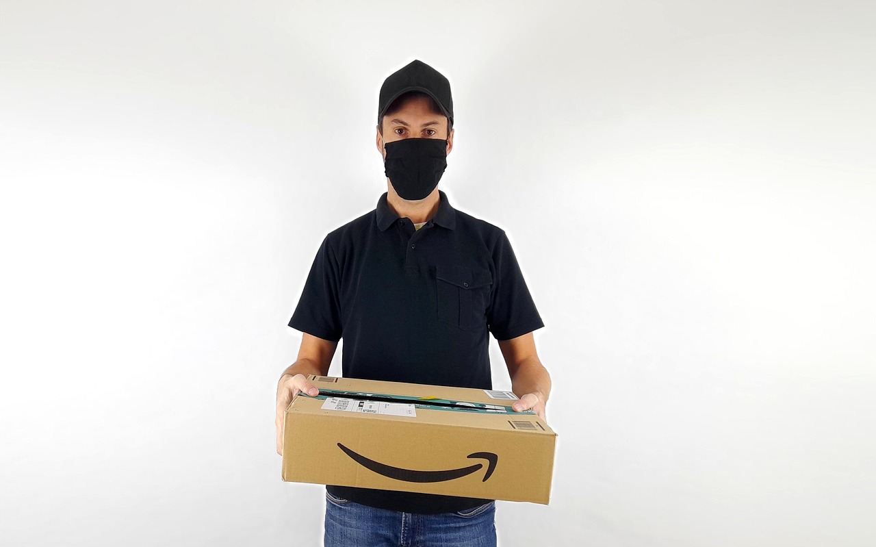 Immagine di un pacco Amazon con un'etichetta di rimborso e un laptop aperto con chat di assistenza clienti.